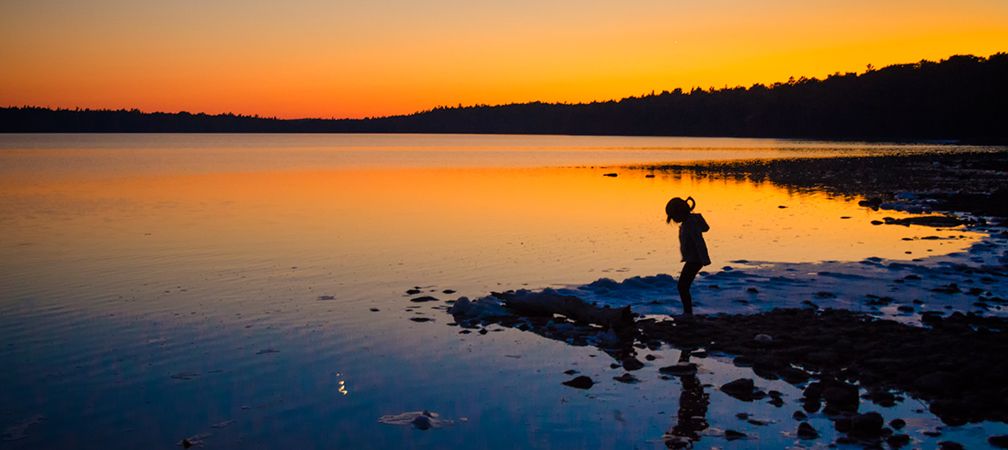 A child explores the Saugeen Peninsula shoreline at sunset